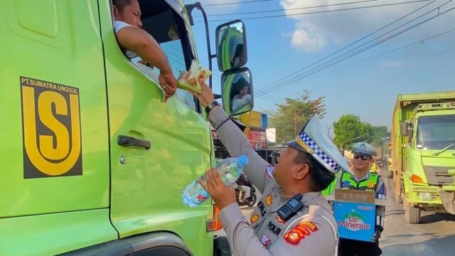 Anggota Polantas Banyuasin membagikan makanan gratis kepada pengendara di tengah kemacetan Jalintim Palembang-Betung.