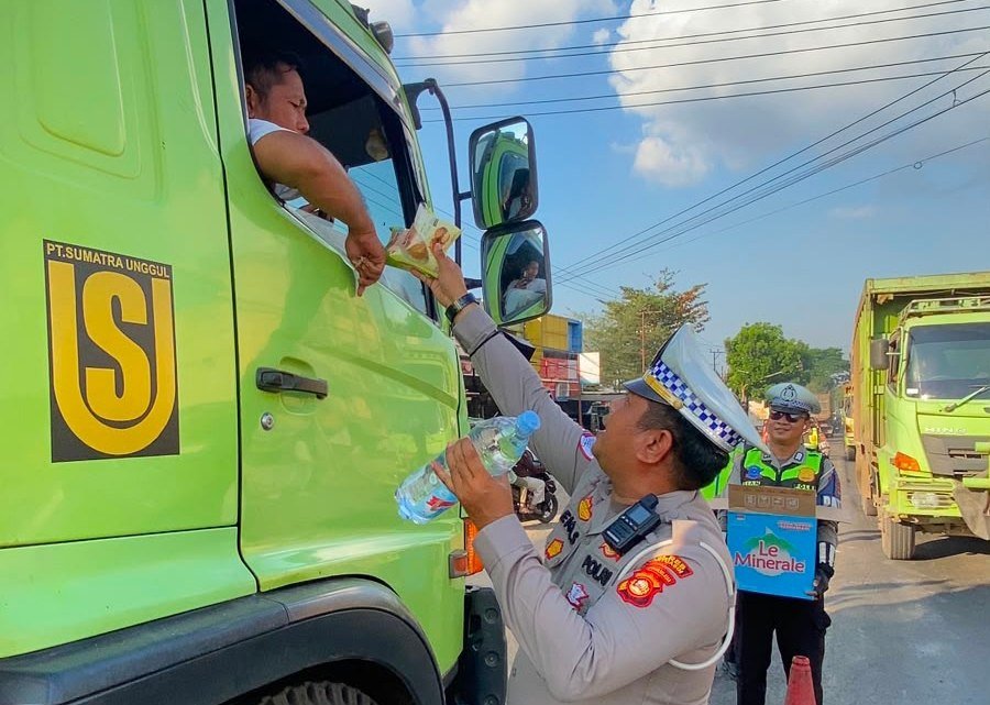 Anggota Polantas Banyuasin membagikan makanan gratis kepada pengendara di tengah kemacetan Jalintim Palembang-Betung.