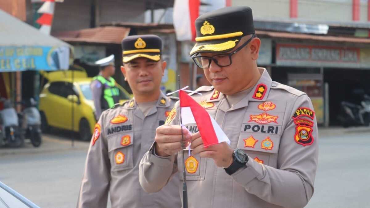 Kapolres PALI AKBP Januar Kencana Setia Persada membagikan bendera Merah Putih kepada warga dalam rangka HUT ke-81 RI.