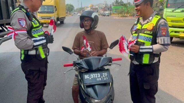 Personel Satlantas Polres Banyuasin bagikan bendera Merah Putih kepada warga di Banyuasin dalam rangka HUT ke-81 RI.