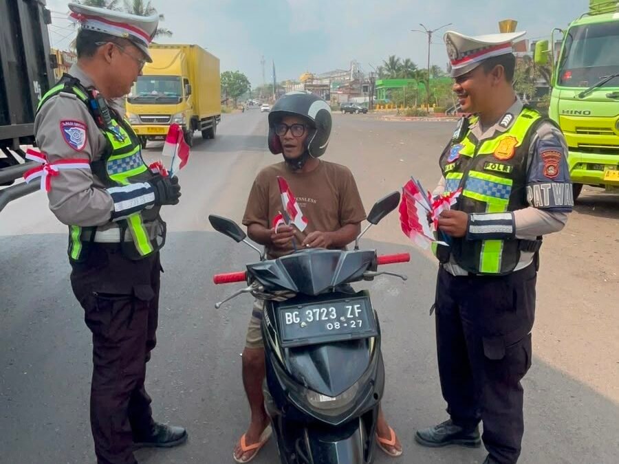 Personel Satlantas Polres Banyuasin bagikan bendera Merah Putih kepada warga di Banyuasin dalam rangka HUT ke-81 RI.