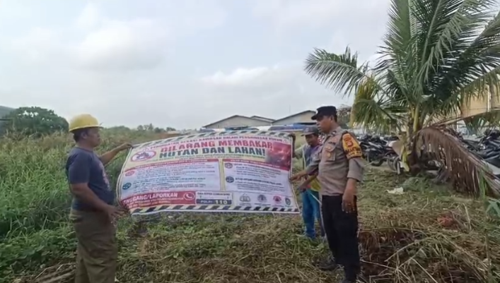 Cegah Kebakaran Lahan, Bhabinkamtibmas Talang Kelapa Pasang Spanduk Karhutla di Jalan Soekarno-Hatta